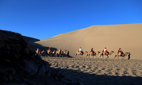 Los turistas visitan la Monta?a Mingsha y el Lago de la Luna Creciente en Gansu 