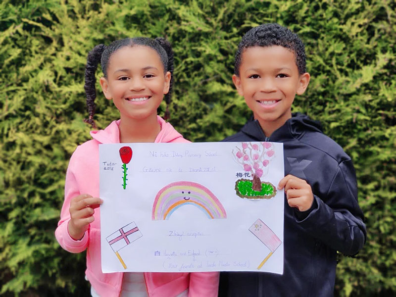 Dos ni?os del Reino Unido muestran un dibujo hecho para los alumnos de la Escuela Primaria Datong de Changsha, provincia Hunan. [Foto: proporcionada a China Daily] 