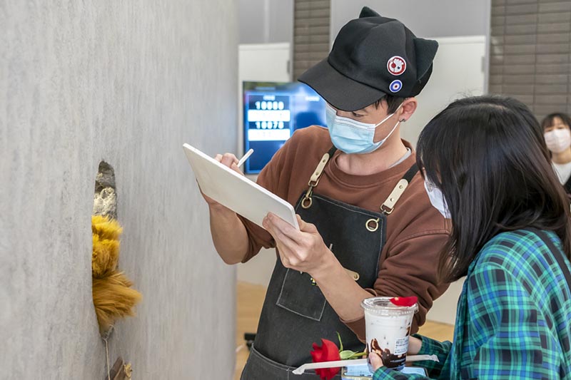 A Ken se comunica con un cliente mediante un tablero de escritura. [Foto: Xinhua]