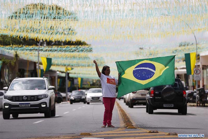 Una mujer cuelga una bandera nacional brasile?a en una calle decorada con motivo de la participación de la selección nacional de fútbol de Brasil en la Copa Mundial de la FIFA Qatar 2022, en Brasilia, Brasil, el 16 de noviembre de 2022. (Xinhua/Lucio Tavora)