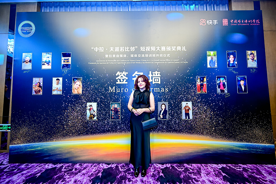 La concursante costarricense Mariana Rodríguez hace una foto frente al muro de firma durante el acto.