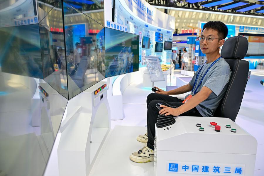 Un miembro del personal opera un simulador de una grúa torre impulsada por 5G en el stand de China Construction Third Engineering Bureau Group en la 8a Exposición China-Eurasia en Urumqi, capital de la región autónoma uygur de Xinjiang, en el noroeste de China, el 26 de junio de 2024. (Xinhua/Ding Lei)