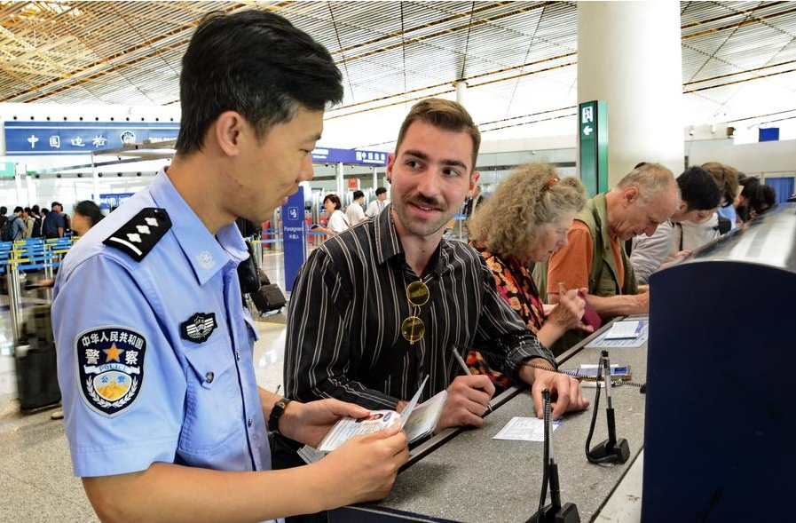 Un agente policial ayuda a un turista estadounidense a completar una tarjeta de registro de entrada en la sección de control fronterizo del Aeropuerto Internacional Capital de Beijing, el 10 de julio de 2024. (Xinhua/Li Xin)