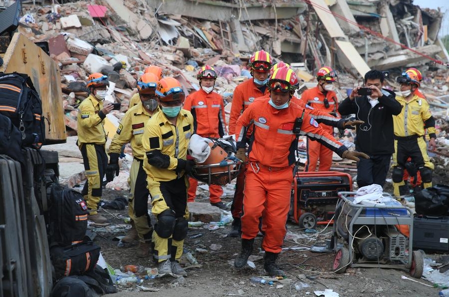 Miembros del equipo chino de Búsqueda y Rescate y del unidad civil de Ramunion Rescue trasladaron conjuntamente a un sobreviviente en un sitio sísmico en Mandalay, Myanmar, el 31 de marzo, 2025. (Xinhua/Myo Kyaw Soe)