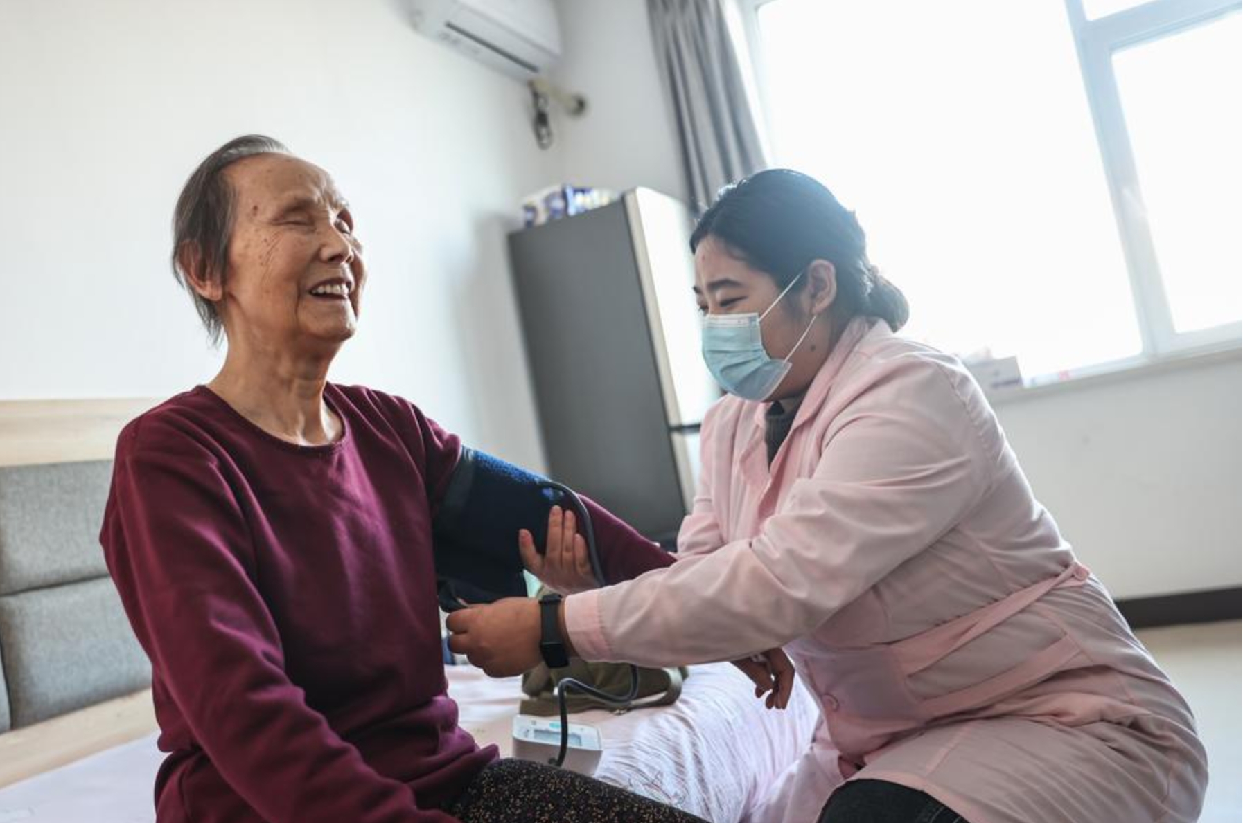 Una trabajadora médica mide la presión arterial de una anciana en el Hogar para la Atención Especializada de Adultos Mayores Haiman en Shenyang, provincia de Liaoning, en el noreste de China, el 7 de enero de 2025. (Xinhua/Pan Yulong)