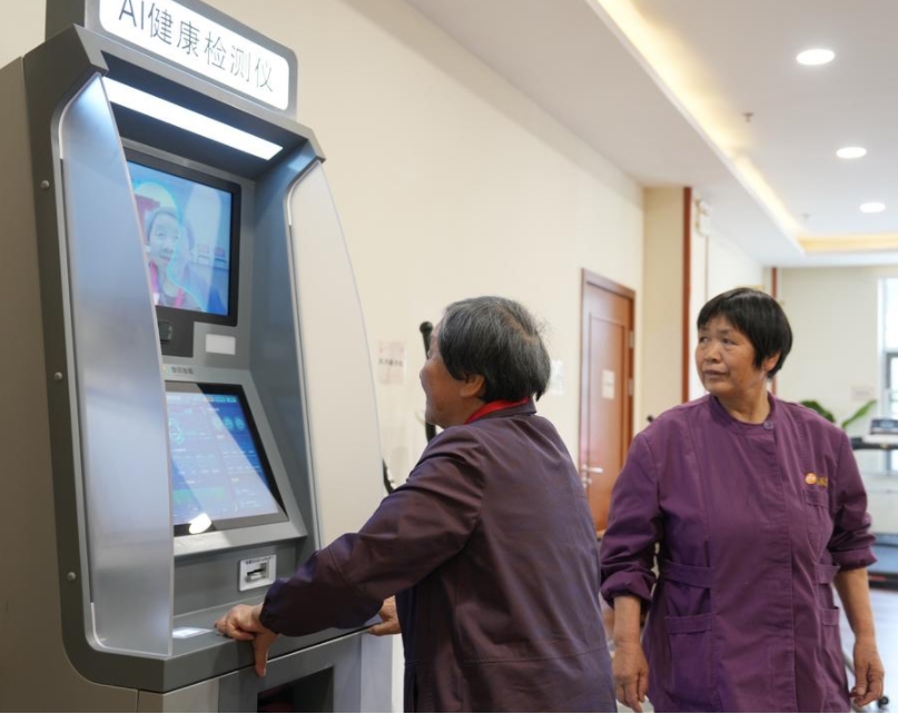 Imagen del 8 de abril de 2025 de una mujer mayor (i) probando un dispositivo de detección de salud con IA con la asistencia de una trabajadora en una casa de retiro, en el distrito de Binghu de Wuxi, en la provincia de Jiangsu, en el este de China. (Xinhua/Liu Wenhui)
