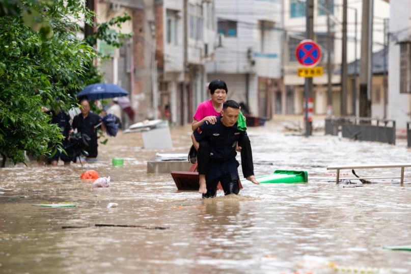 Un rescatista ayuda a evacuar a una mujer de la tercera edad desde un área afectada por inundaciones, en el distrito de Congjiang de la provincia suroccidental china de Guizhou, el 24 de junio de 2025. (Xinhua/Wu Xingke)